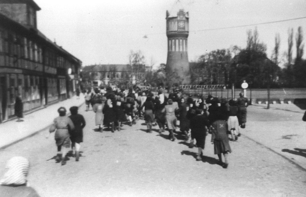 Eine Gruppe von männlichen und weiblichen KZ-Häftlingen von hinten zu sehen